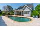 Backyard view of the in-ground pool with stone border, patio, covered porch and partial home view at 125 Swayne Dr, Mooresville, NC 28117
