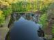 Aerial shot of a large pond surrounded by lush trees, reflecting the sky, creating a peaceful scene at 15670 Bethel Avenue Ext, Midland, NC 28107