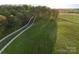 Scenic aerial view of a long driveway leading to horse farm with fenced pastures and lush green landscape at 15670 Bethel Avenue Ext, Midland, NC 28107