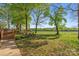 Landscaped backyard with a deck and manicured lawn area, white fence, and tree-lined perimeter at 15670 Bethel Avenue Ext, Midland, NC 28107