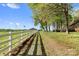 Long driveway lined with a white fence and mature trees leading to a barn and house at 15670 Bethel Avenue Ext, Midland, NC 28107