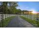 The long paved driveway is flanked by a white fence, leading to the main house on the farm at 15670 Bethel Avenue Ext, Midland, NC 28107