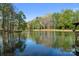 Scenic view of a calm pond reflecting the surrounding trees and sky, with a wooden dock at 15670 Bethel Avenue Ext, Midland, NC 28107