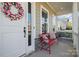 Cozy front porch seating with a red bench, decorative pillows, and an inviting view of the neighborhood at 164 Riverstone Dr, Davidson, NC 28036