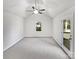 A well-lit room with neutral walls, carpeted floors, ceiling fan, and a door to the outside at 1727 Running Brook Rd, Charlotte, NC 28214