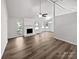 Spacious living room featuring wood-look flooring, a white brick fireplace, and access to the back patio at 1727 Running Brook Rd, Charlotte, NC 28214