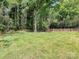 Large backyard with level lawn, mature trees, fencing, and a playset at 3324 Champaign St, Charlotte, NC 28210