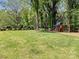 Spacious backyard featuring lush green grass, mature trees, and a fun playset at 3324 Champaign St, Charlotte, NC 28210