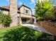 Exterior home view from yard featuring stone patio, brick wall, and neutral siding with black trim at 703 Sainte Rose Ln, Charlotte, NC 28226