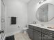 Modern bathroom with gray cabinets, a round mirror, and a glass-enclosed shower providing a spa-like experience at 811 Penny Royal Ave, Fort Mill, SC 29715