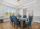 Elegant dining room with blue upholstered chairs, wood floors and modern light fixture at 811 Penny Royal Ave, Fort Mill, SC 29715