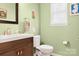 Powder room featuring green walls, a wood vanity, and framed mirror at 103 Claremont Way, Mooresville, NC 28117