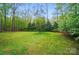 Sprawling backyard featuring lush lawn, mature trees and bordered by a wooden fence at 109 Canterbury Ln, Matthews, NC 28104