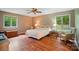 Bedroom with wood floor, neutral walls, three windows with views of trees, and wicker furniture at 109 Canterbury Ln, Matthews, NC 28104