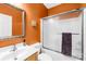 Bathroom with an orange wall, a sink, toilet, a shower with glass door and a decorative mirror at 130 Weeping Spring Dr, Mooresville, NC 28115