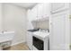 Functional laundry room with a sink, white cabinets, and modern washing and drying machines at 130 Weeping Spring Dr, Mooresville, NC 28115