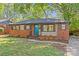Delightful brick house featuring a teal door, stone details, mature trees, and a lush front lawn at 1330 Dean St, Charlotte, NC 28216