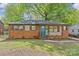 Charming brick home with a vibrant turquoise door, complemented by stone accents and a well-maintained front yard at 1330 Dean St, Charlotte, NC 28216