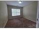 A standard bedroom featuring neutral-toned walls, carpeting, and a bright window at 13409 Glasgow Green Ln, Charlotte, NC 28213