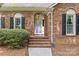 Close-up of brick home entrance featuring a stylish purple door, brick steps, and lush shrubs at 2234 Hamilton Mill Rd, Charlotte, NC 28270