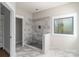 Modern walk-in shower with marble-look tile and contrasting pebble floor, enhanced by natural light from the window at 2596 Polo Ln, Maiden, NC 28650