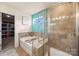 Stylish bathroom featuring a tub, glass shower, and beige tile; organized closet visible at 269 Keating Place Dr, Fort Mill, SC 29708