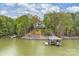 Scenic view of a charming lakeside home surrounded by lush greenery and mature trees at 272 Harbor Ridge Dr, Statesville, NC 28677