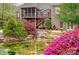 Lush backyard featuring a pond, waterfall, brick home, and verdant landscaping at 305 Caledonia Way, Waxhaw, NC 28173