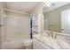 Bright bathroom featuring a tub with tiled surround, storage shelves, and a marble countertop vanity at 368 Northwest Dr, Davidson, NC 28036