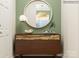 Stylish entryway with a modern wood cabinet, round mirror, and decor against a green wall at 4551 Potters Wheel Dr, Fort Mill, SC 29715