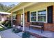 Inviting front porch with brick accents, an iron bench, and manicured landscaping at 5381 Mount Carmel Rd, Heath Springs, SC 29058