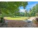 Lush backyard view, featuring a tranquil lake, stone bridge, and manicured landscaping at 542 Lochaven Rd, Waxhaw, NC 28173