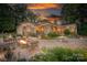 Inviting outdoor space with stone patio, fire pit, seating, and lush landscaping at sunset at 542 Lochaven Rd, Waxhaw, NC 28173