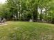 Expansive backyard with mature trees, lush green lawn, a shed, and plenty of space for outdoor activities at 7820 Elm Tree Ln, Charlotte, NC 28227