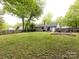 Spacious backyard featuring a lush green lawn, mature trees, and a fenced garden area at 7820 Elm Tree Ln, Charlotte, NC 28227
