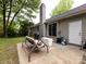 Backyard patio featuring a charming swing bench, grill, sliding door access, and a brick chimney at 7820 Elm Tree Ln, Charlotte, NC 28227