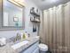 Stylish bathroom with a granite countertop, a vanity, a toilet, and shelves with decorative items at 7820 Elm Tree Ln, Charlotte, NC 28227
