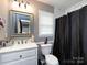 The bathroom features a vanity, toilet, mirror, and a shower with a dark shower curtain at 7820 Elm Tree Ln, Charlotte, NC 28227