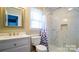 Bright bathroom with white marble-look shower, a white vanity, toilet, and framed mirror at 7820 Elm Tree Ln, Charlotte, NC 28227