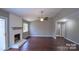 Spacious living room with a white painted fireplace, hardwood flooring, and large windows that bring in natural light at 7820 Elm Tree Ln, Charlotte, NC 28227