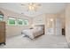 Well-lit bedroom featuring carpet, a ceiling fan, a connecting door to a bathroom, and natural light at 7822 Village Harbor Dr, Cornelius, NC 28031