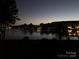 Nighttime view of the lake with community lights reflecting on the water at 7822 Village Harbor Dr, Cornelius, NC 28031