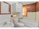 Traditional bathroom featuring a tub with orange curtain, toilet, and sink with mirrored medicine cabinet at 834 Murphy St, Kannapolis, NC 28081
