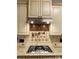 Close-up of a cooktop with a stainless steel range hood and tile backsplash at 9113 Oak Bluff Ct, Waxhaw, NC 28173