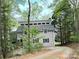 Exterior view of multi-story home nestled among mature trees and winding driveway at 1224 Island Creek Dr, Troy, NC 27371