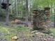 Stacked stone outdoor fireplace feature in wooded backyard of home at 1224 Island Creek Dr, Troy, NC 27371