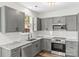 Modern kitchen with gray cabinets, granite countertops, and stainless appliances at 13206 Meadowmere Rd, Huntersville, NC 28078
