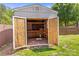 A storage shed on a grassy lot with open door and wooden shelving at 13206 Meadowmere Rd, Huntersville, NC 28078