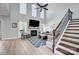 Sun-filled living room with soaring ceilings, a cozy fireplace, a ceiling fan, and elegant staircase at 15407 Saxon Trace Ct, Huntersville, NC 28078