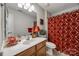 Cozy bathroom with wood vanity, and a shower featuring a patterned red shower curtain at 15613 Troubadour Ln, Huntersville, NC 28078
